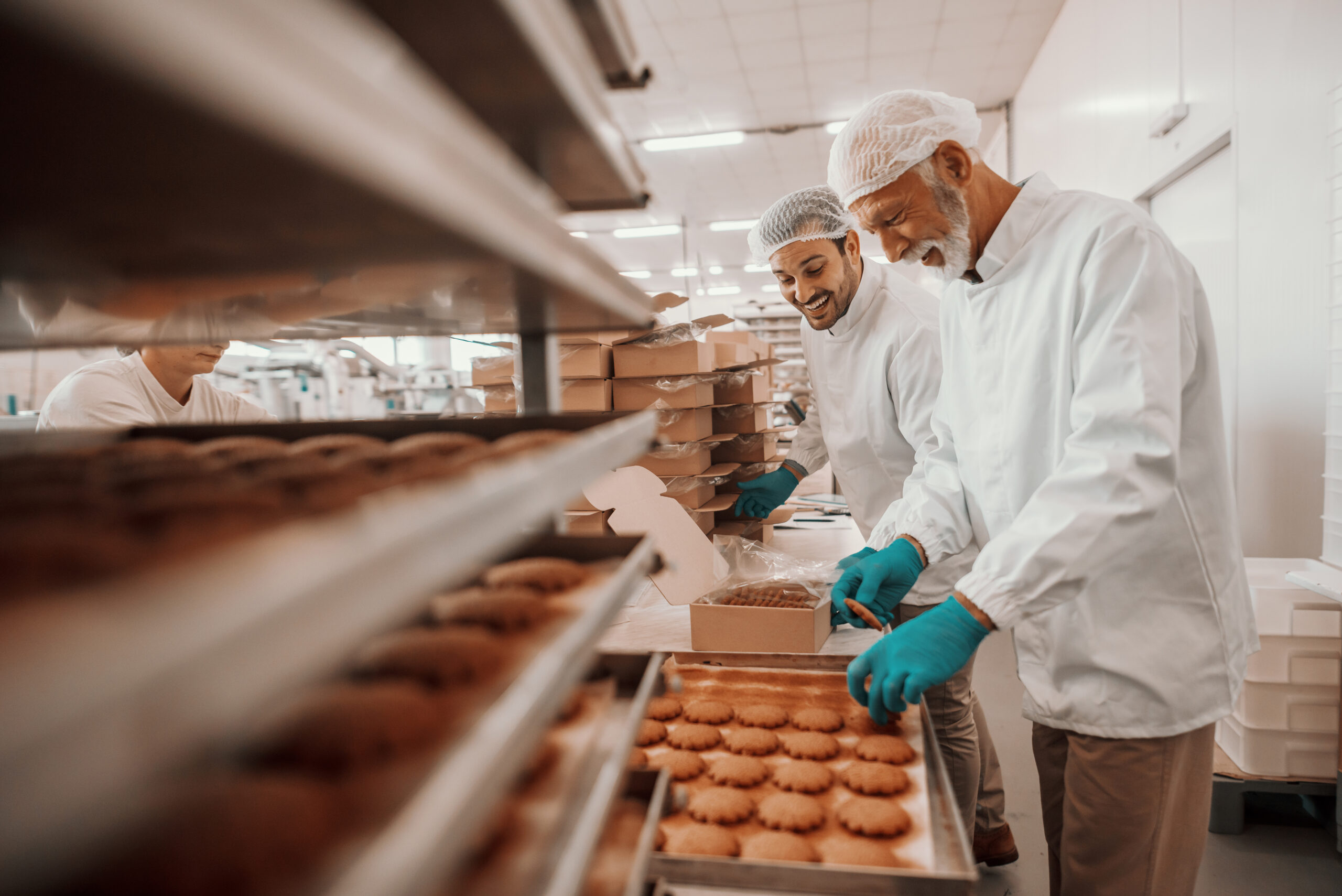 Two employees working in a bakery packing products in solid board trays