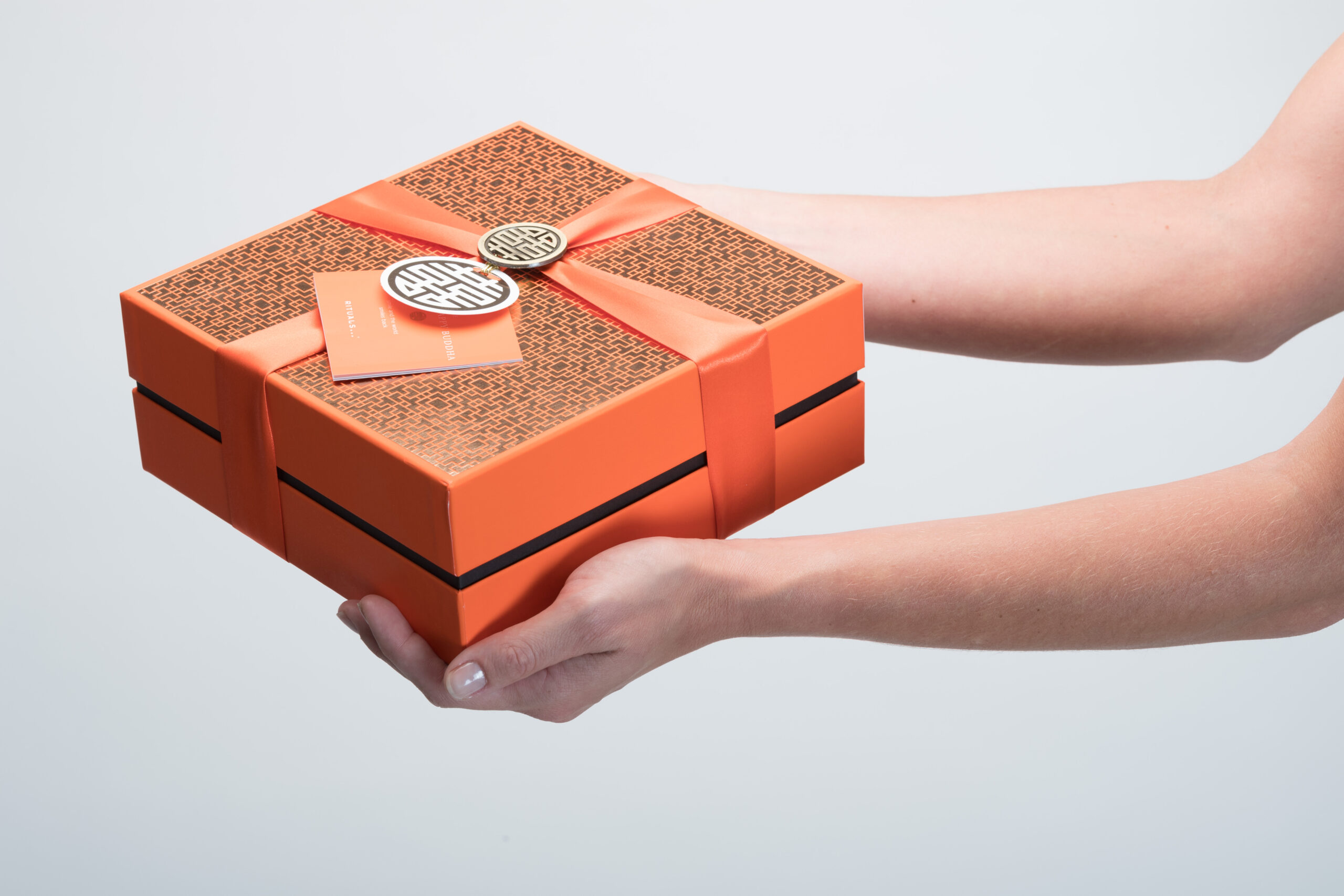 Oranje/zalm kleurige Luxline specialiteiten voor cosmetische verpakkingen vast in twee handen • Solidus