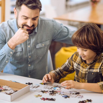 Happy father watching his son play with a puzzle • Solidus